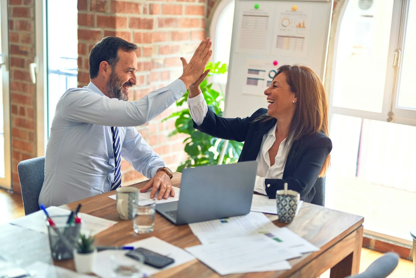Two colleagues celebrating a win together at a desk